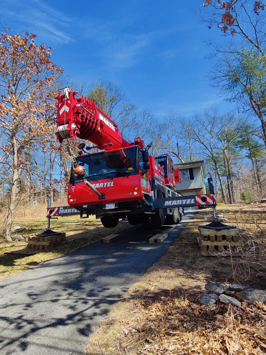 We setup the red crane in the driveway of this residence in Chelmsford, MA to safely remove trees from the property.