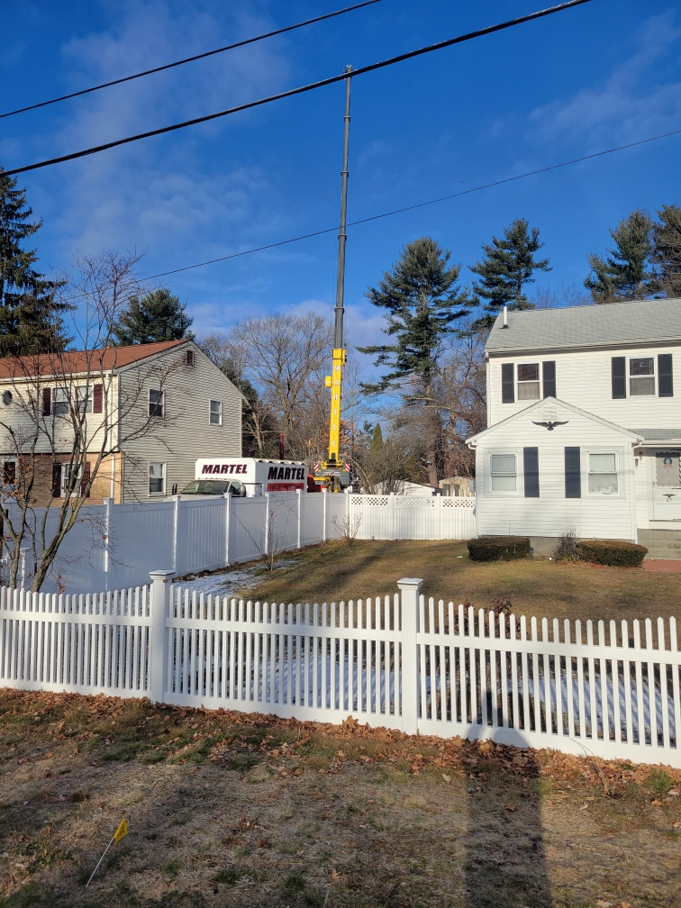 The crew from Martel Crane & Tree set up the crane in the side yard to remove large pines from the backyard of this residence in Billerica, MA.

